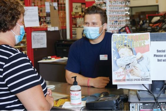 employee wearing mask helping customer at checkout