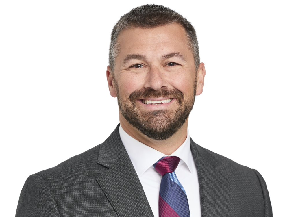 Smiling man in a dark suit and striped tie facing the camera (professional headshot).